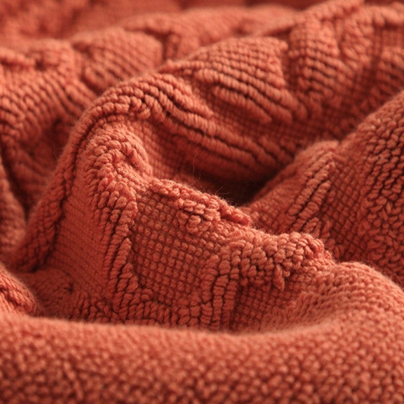 Thick cotton bath mat with textured weave in warm terracotta color.