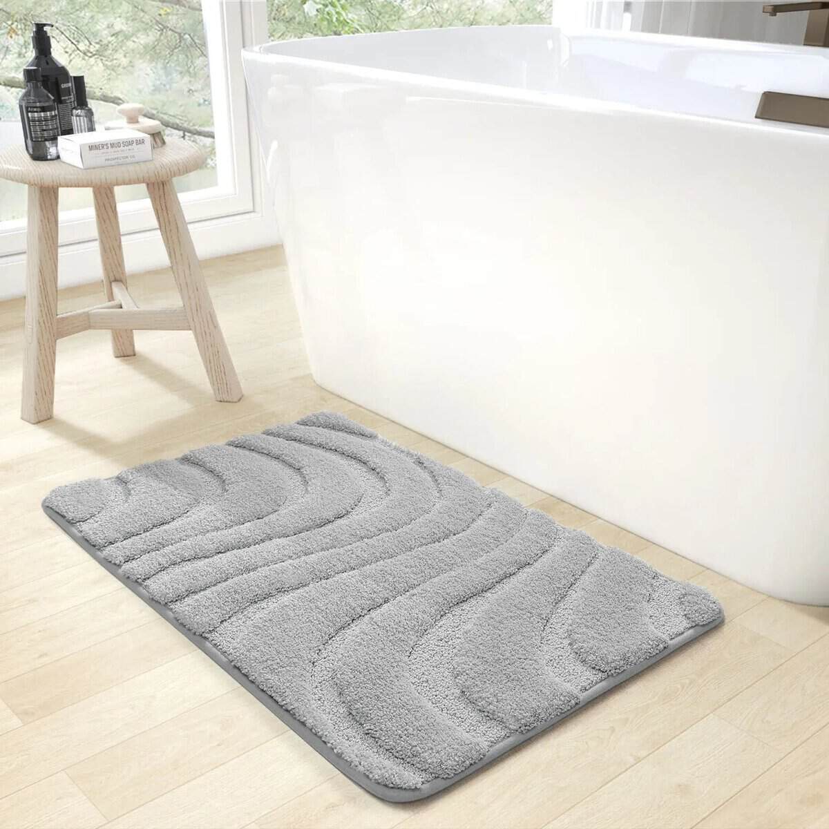 Thick grey bath mat with wavy texture for modern bathroom.
