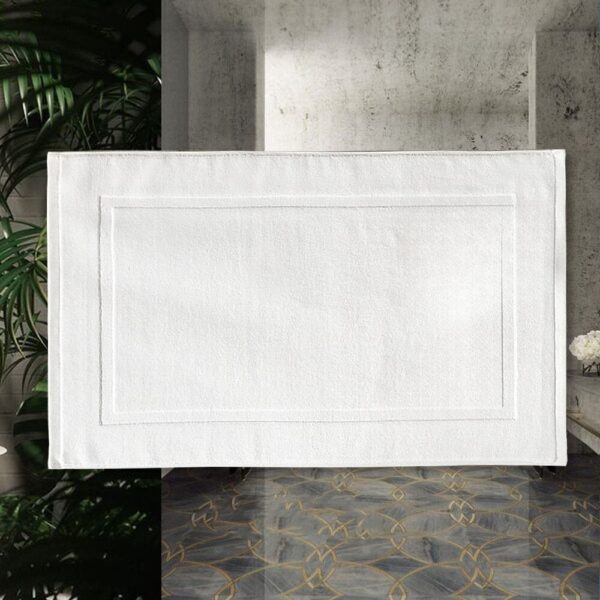 White cotton bath mat with stitched border for luxury bathroom.